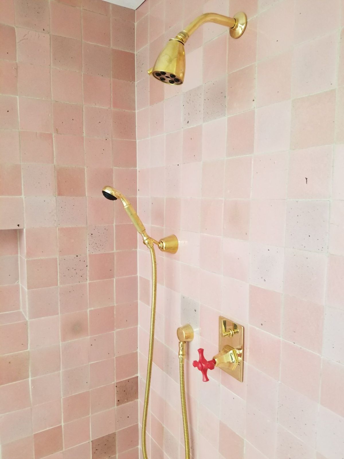 Close view of brass shower fixtures on pink tile