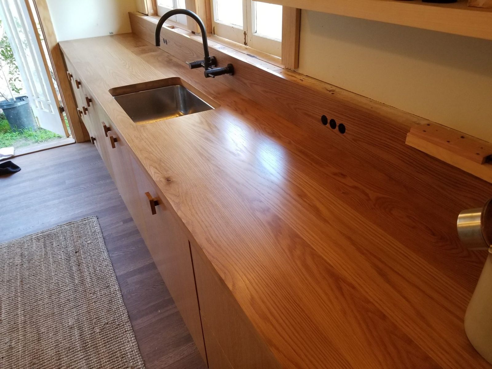 Kitchen with a long solid wood counter and wood cabinets under a window