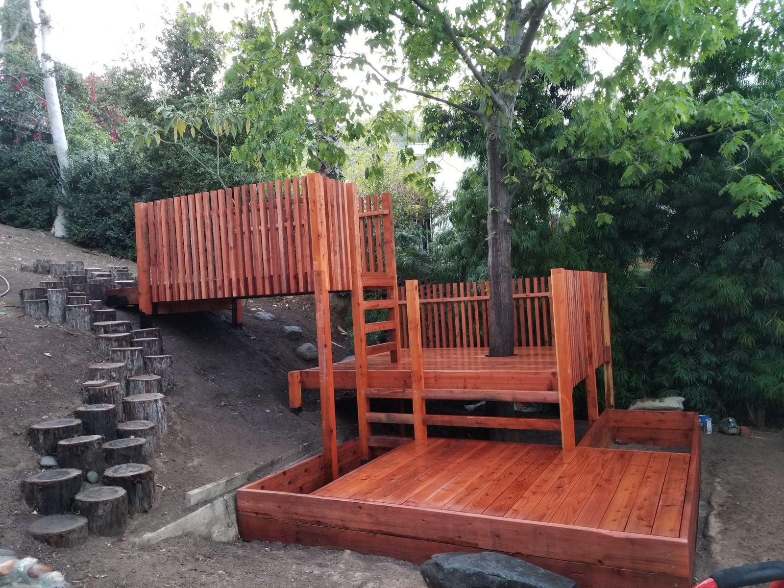 Play structure platforms with log steps leading up the slope