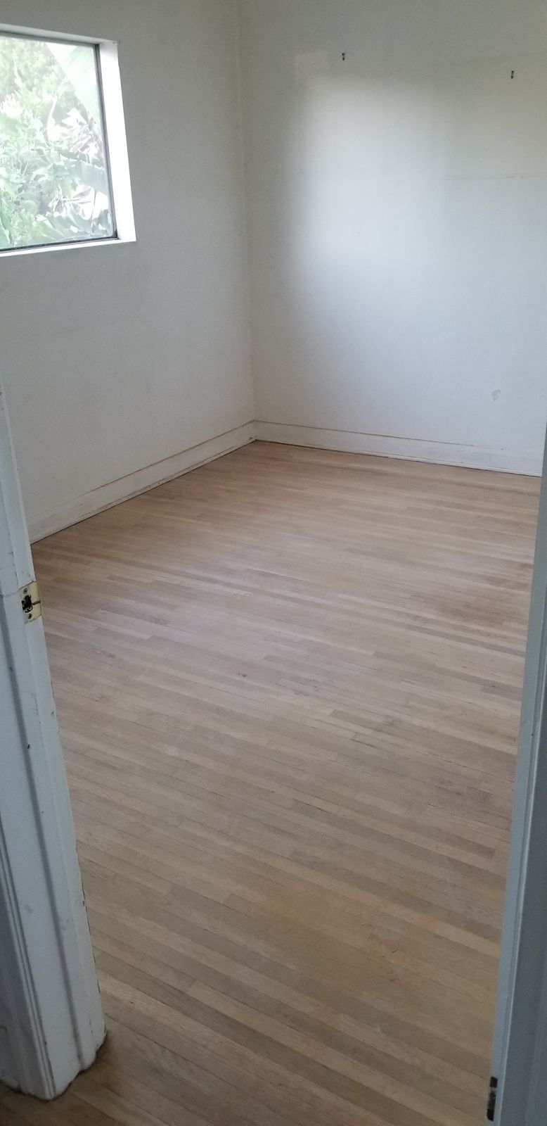 Before: dull hardwood floor in an empty bedroom