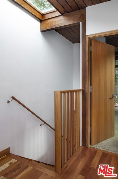 Stair landing with a wood railing under a skylight