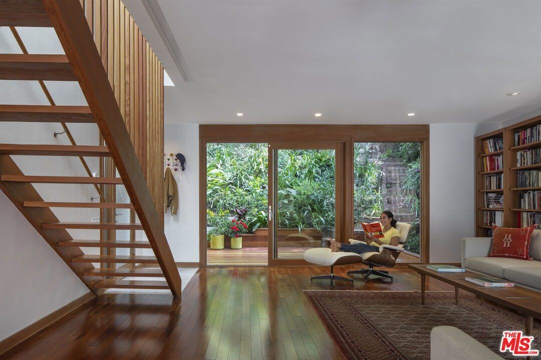 Living room with an open wood staircase and glass doors to the garden