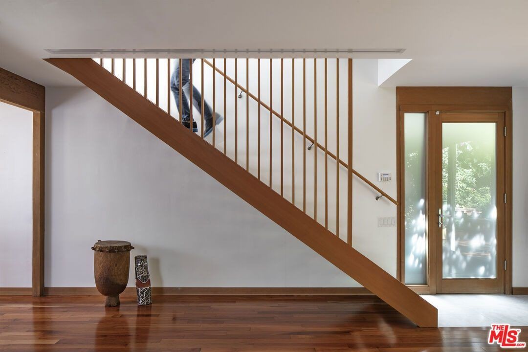 Wood staircase with vertical slats beside a white wall